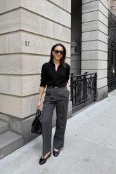 a lady in a black shirt and a pair of grey pants